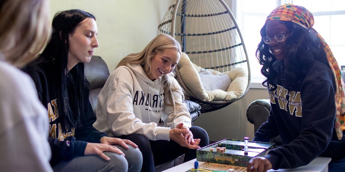 Four young women around a coffee table in a living room playing a game.