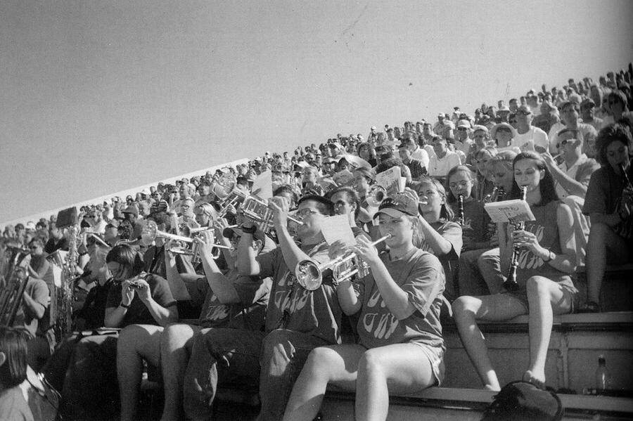 Band members in the bleachers playing their instruments.